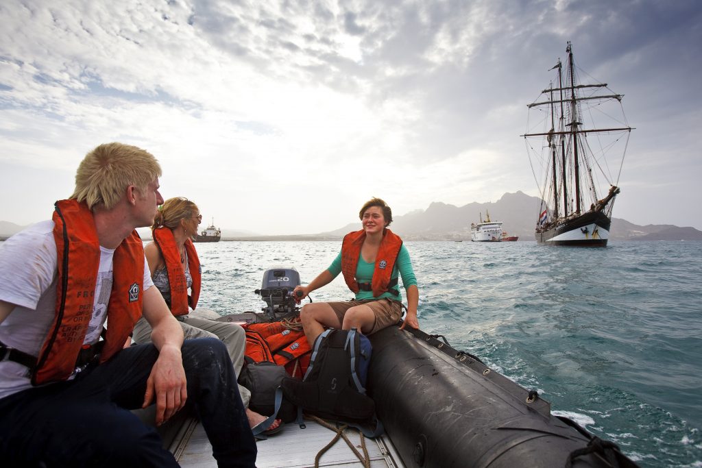 Trainees in a dinghy with Tall Ship Oosterschelde in the background
