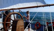 Photo of a young woman steering a large Tall Ship (Wylde Swan)