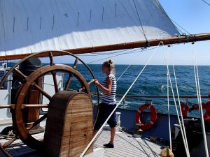 Photo of a young woman steering a large Tall Ship (Wylde Swan)